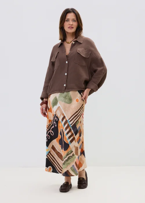 Brązowa lniana koszula oversize z kieszeniami na piersi i guzikami, lekka i naturalna, stylizowana z wzorzystą spódnicą w casualowym looku.