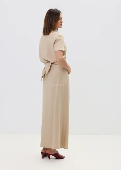 Beżowa spódnica z kopertowym wiązaniem w talii, o płynnie układającym się fasonie, elegancka i minimalistyczna w stylizacji z sandałami na obcasie.