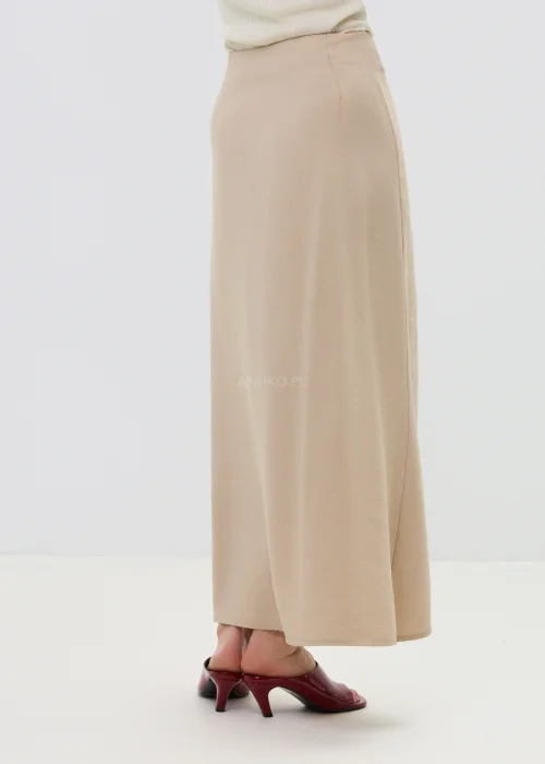 Beżowa spódnica z kopertowym wiązaniem w talii, o płynnie układającym się fasonie, elegancka i minimalistyczna w stylizacji z sandałami na obcasie.