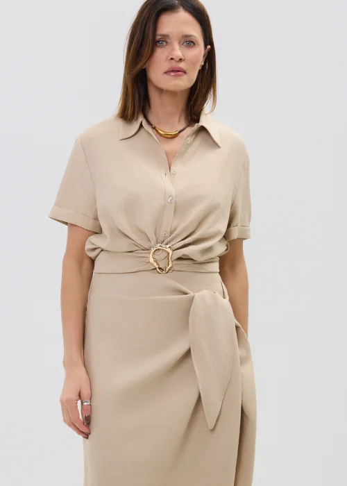 Beżowa bluzka damska z krótkim rękawem i ozdobnym wiązaniem z klamrą, lekka i elegancka.