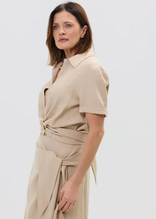 Beżowa bluzka damska z krótkim rękawem i ozdobnym wiązaniem z klamrą, lekka i elegancka.