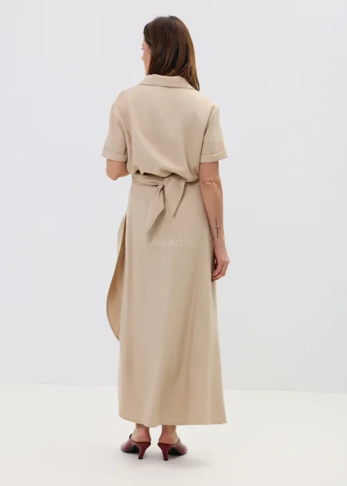 Beżowa bluzka damska z krótkim rękawem i ozdobnym wiązaniem z klamrą, lekka i elegancka.