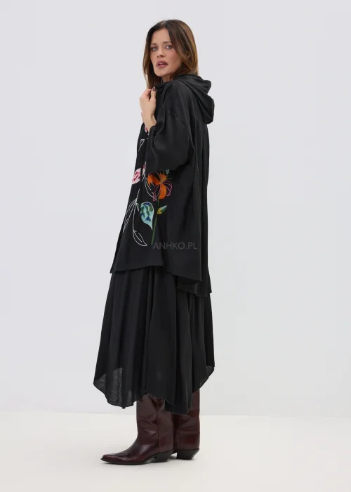 Czarna spódnica midi o zwiewnym kroju z asymetrycznym dołem, stylizowana z wysokimi botkami w eleganckim wydaniu.