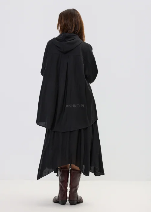 Czarna spódnica midi o zwiewnym kroju z asymetrycznym dołem, stylizowana z wysokimi botkami w eleganckim wydaniu.