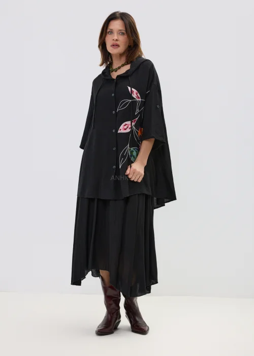 Czarna spódnica midi o zwiewnym kroju z asymetrycznym dołem, stylizowana z wysokimi botkami w eleganckim wydaniu.