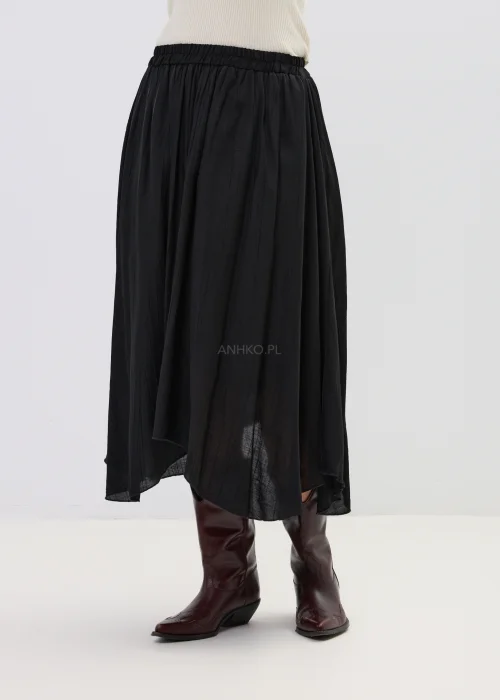Czarna spódnica midi o zwiewnym kroju z asymetrycznym dołem, stylizowana z wysokimi botkami w eleganckim wydaniu.