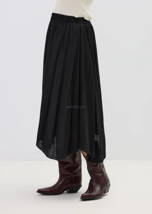 Czarna spódnica midi o zwiewnym kroju z asymetrycznym dołem, stylizowana z wysokimi botkami w eleganckim wydaniu.