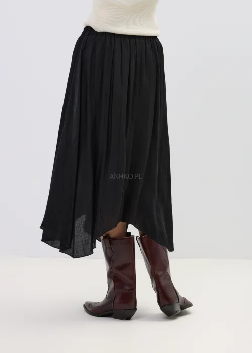 Czarna spódnica midi o zwiewnym kroju z asymetrycznym dołem, stylizowana z wysokimi botkami w eleganckim wydaniu.