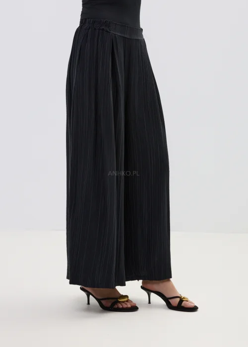 Czarne spodnie damskie w delikatny prążek z szeroką nogawką i elastyczną talią, o luźnym, eleganckim kroju w minimalistycznej stylizacji.