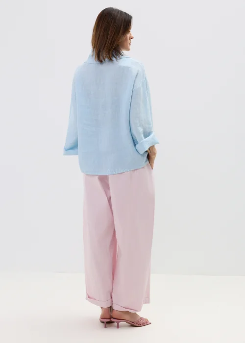 Różowe spodnie damskie z szerokimi nogawkami i podwiniętym dołem, luźny fason, elegancko-casualowa stylizacja.