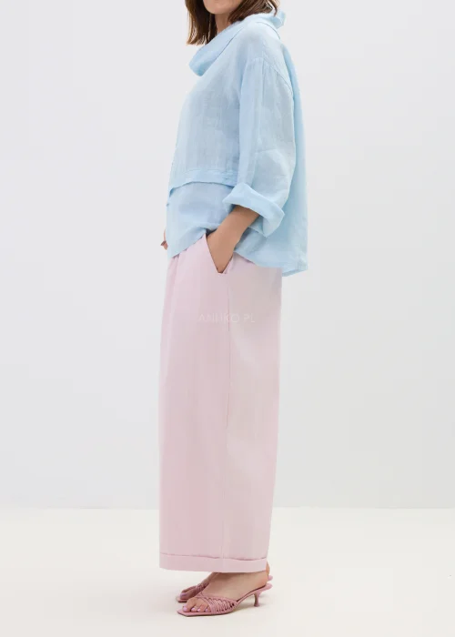 Różowe spodnie damskie z szerokimi nogawkami i podwiniętym dołem, luźny fason, elegancko-casualowa stylizacja.