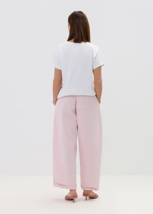 Różowe spodnie damskie z szerokimi nogawkami i podwiniętym dołem, luźny fason, elegancko-casualowa stylizacja.