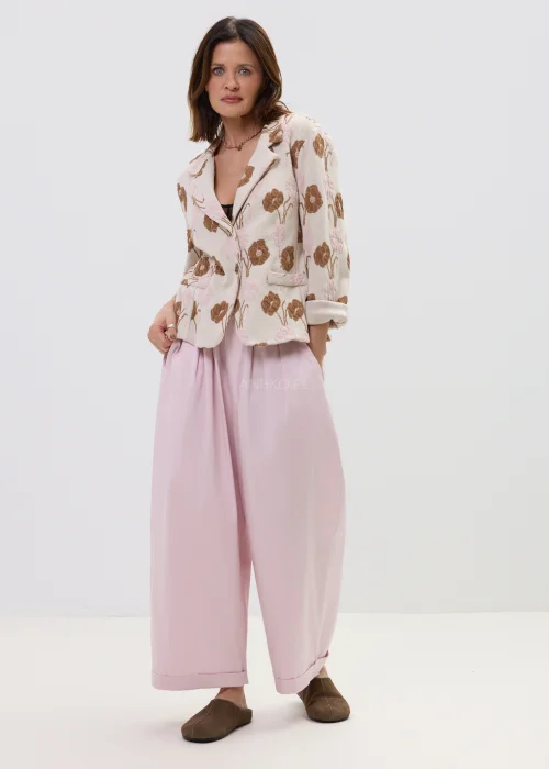 Różowe spodnie damskie z szerokimi nogawkami i podwiniętym dołem, luźny fason, elegancko-casualowa stylizacja.