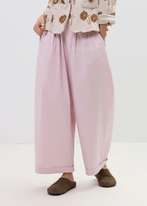 Różowe spodnie damskie z szerokimi nogawkami i podwiniętym dołem, luźny fason, elegancko-casualowa stylizacja.