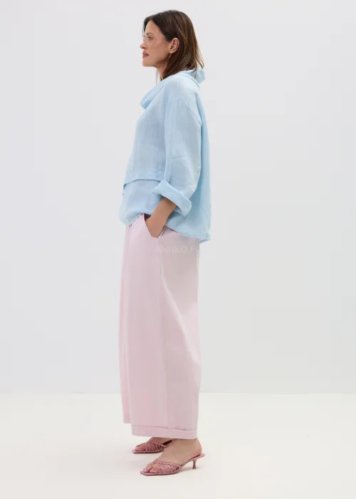 Lniana bluzka damska w kolorze błękitnym, o luźnym kroju z szerokim rękawem i miękkim kołnierzem, stylizowana z różowymi spodniami w minimalistycznym looku.