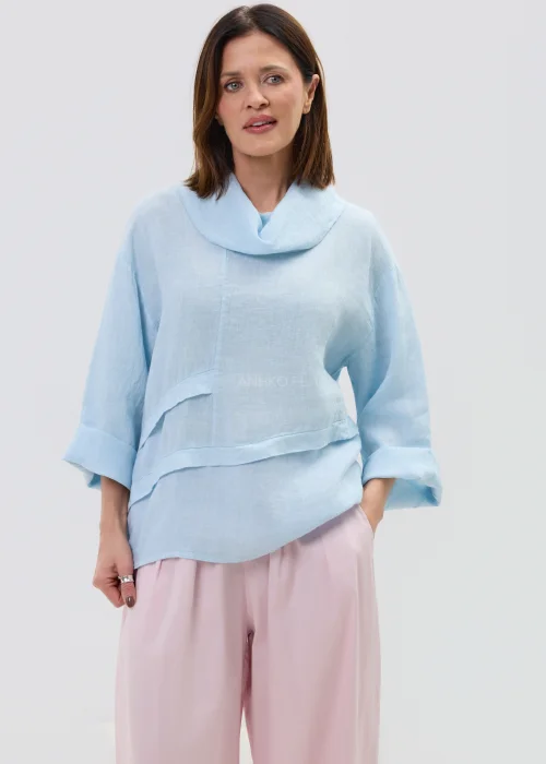 Lniana bluzka damska w kolorze błękitnym, o luźnym kroju z szerokim rękawem i miękkim kołnierzem, stylizowana z różowymi spodniami w minimalistycznym looku.