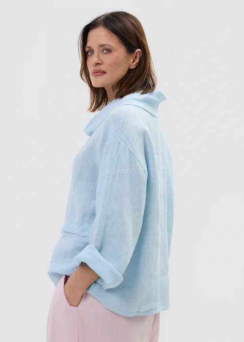 Lniana bluzka damska w kolorze błękitnym, o luźnym kroju z szerokim rękawem i miękkim kołnierzem, stylizowana z różowymi spodniami w minimalistycznym looku.