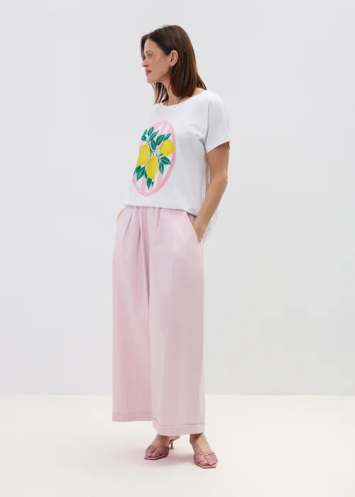 Biały t-shirt damski z nadrukiem cytryn i zielonych liści, o luźnym kroju, stylizowany z różowymi spodniami w casualowym looku.