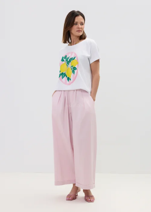 Biały t-shirt damski z nadrukiem cytryn i zielonych liści, o luźnym kroju, stylizowany z różowymi spodniami w casualowym looku.