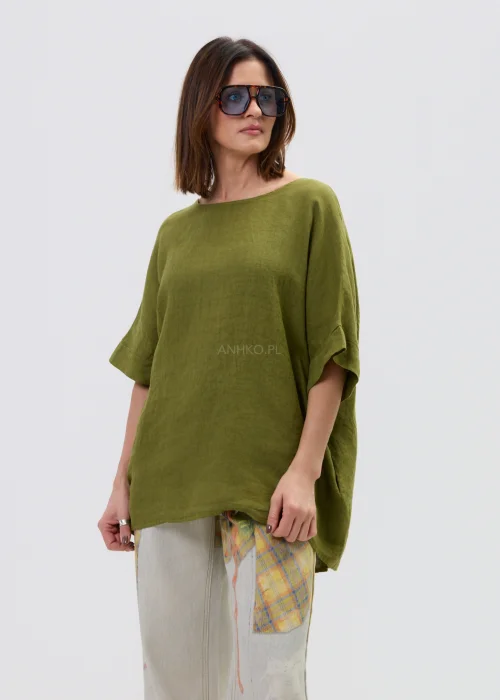 Lniana bluzka oversize w kolorze oliwkowej zieleni z krótkim rękawem i wiązaniem oraz guzikami na plecach, o luźnym kroju, stylizowana z jasnymi spodniami.
