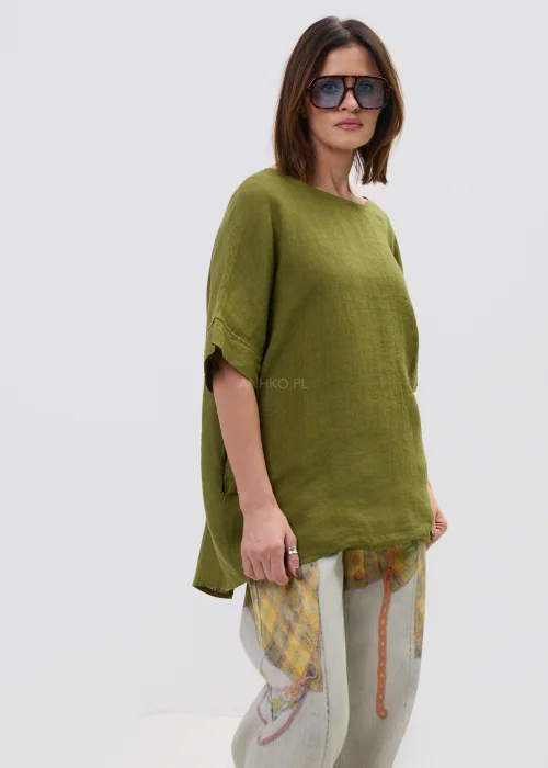 Lniana bluzka oversize w kolorze oliwkowej zieleni z krótkim rękawem i wiązaniem oraz guzikami na plecach, o luźnym kroju, stylizowana z jasnymi spodniami.