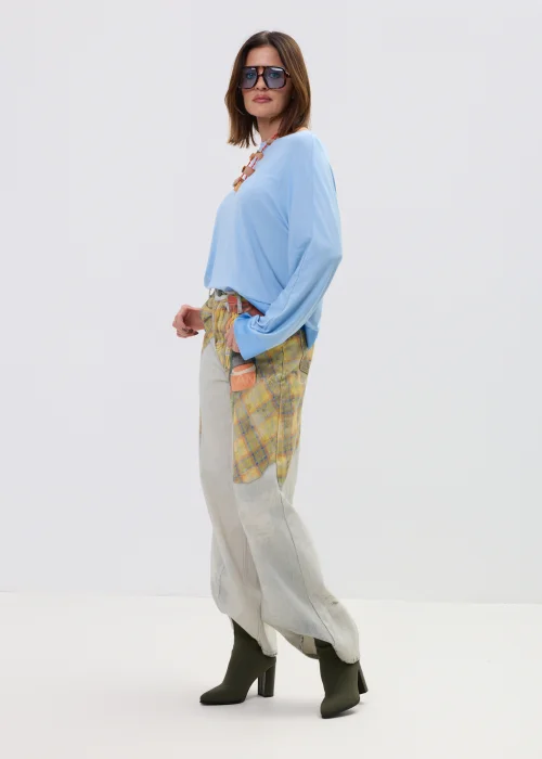 Niebieska bluzka damska o luźnym kroju z długim rękawem i szerokim dekoltem, lekki materiał, casualowa stylizacja.