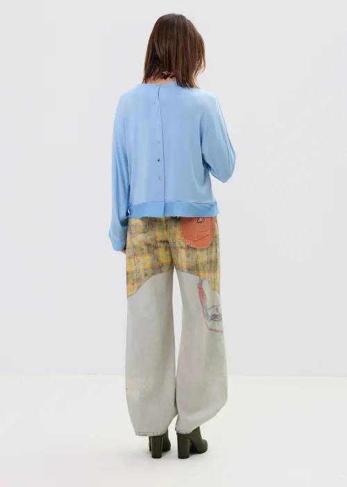 Niebieska bluzka damska o luźnym kroju z długim rękawem i szerokim dekoltem, lekki materiał, casualowa stylizacja.