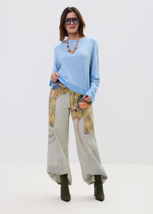 Niebieska bluzka damska o luźnym kroju z długim rękawem i szerokim dekoltem, lekki materiał, casualowa stylizacja.