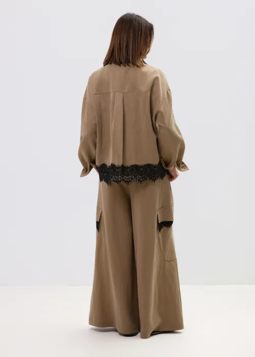 Koszula oversize w kolorze brązowym z czarną koronką przy kołnierzu i dole, o luźnym kroju z długim rękawem.