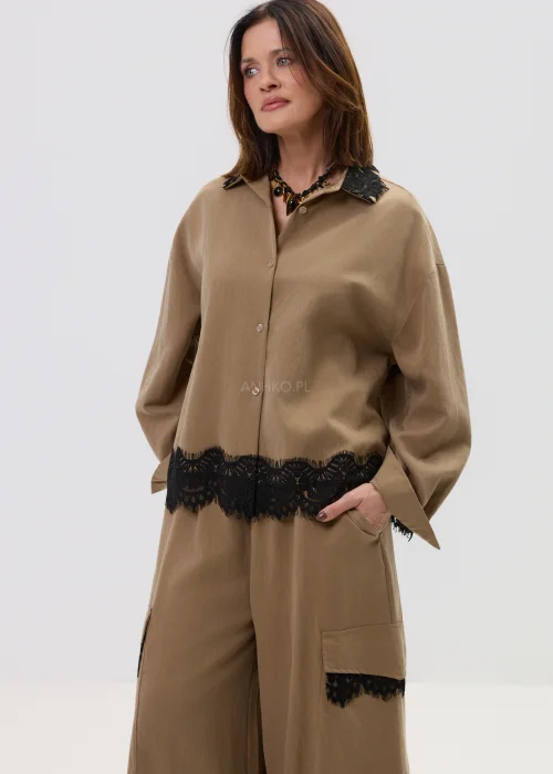 Koszula oversize w kolorze brązowym z czarną koronką przy kołnierzu i dole, o luźnym kroju z długim rękawem.