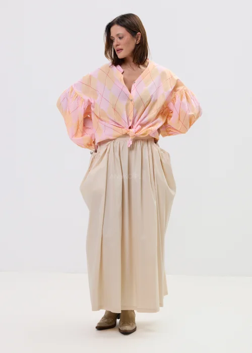 Koszula oversize w pastelową kratę w odcieniach różu i pomarańczu, z bufiastymi rękawami i wiązaniem z przodu, stylizowana z długą beżową spódnicą w kobiecym, lekkim looku.