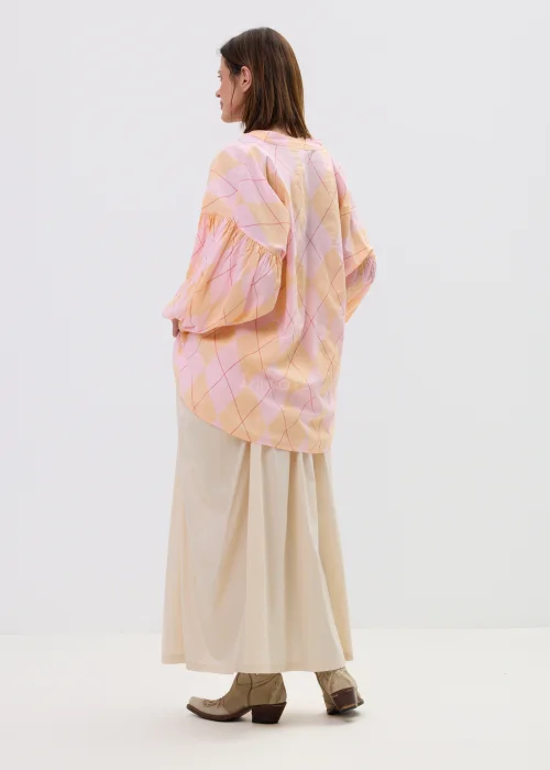 Koszula oversize w pastelową kratę w odcieniach różu i pomarańczu, z bufiastymi rękawami i wiązaniem z przodu, stylizowana z długą beżową spódnicą w kobiecym, lekkim looku.