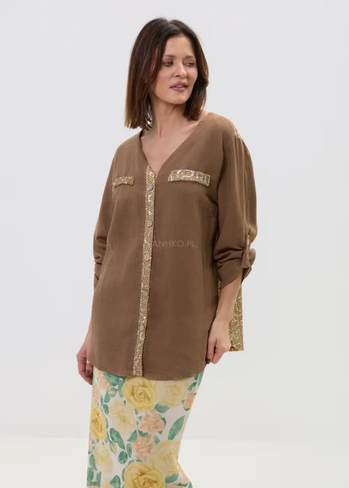 Lniana koszula oversize w kolorze brązowym z cekinowymi zdobieniami i kieszeniami, z długim rękawem i zapięciem na guziki, stylizowana z kwiatową spódnicą.