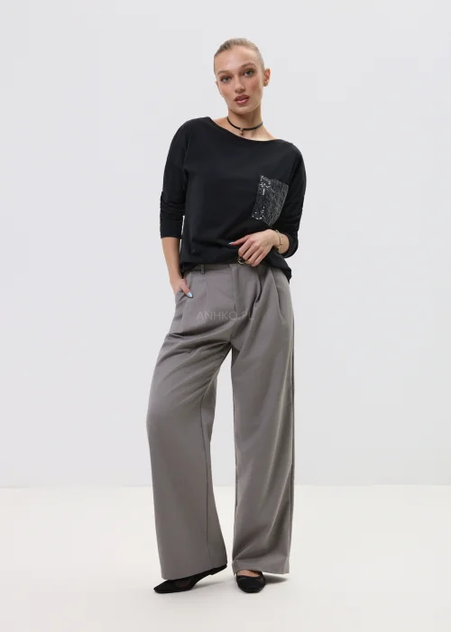 Czarna bluzka damska z długim rękawem i kieszonką zdobioną cekinami, luźny fason, elegancko-casualowa stylizacja.