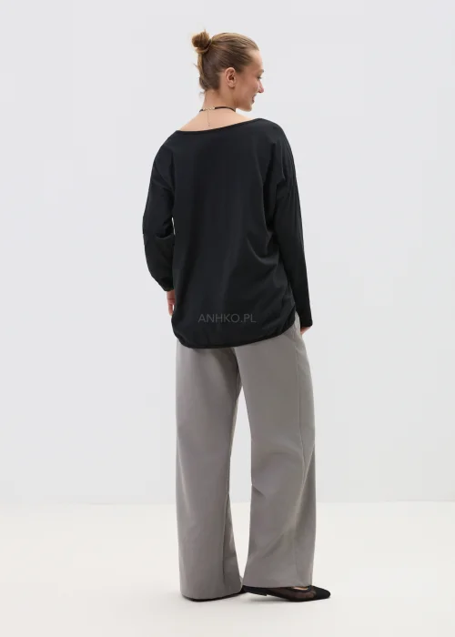 Czarna bluzka damska z długim rękawem i kieszonką zdobioną cekinami, luźny fason, elegancko-casualowa stylizacja.