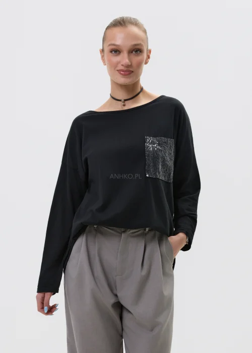 Czarna bluzka damska z długim rękawem i kieszonką zdobioną cekinami, luźny fason, elegancko-casualowa stylizacja.