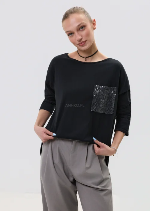 Czarna bluzka damska z długim rękawem i kieszonką zdobioną cekinami, luźny fason, elegancko-casualowa stylizacja.