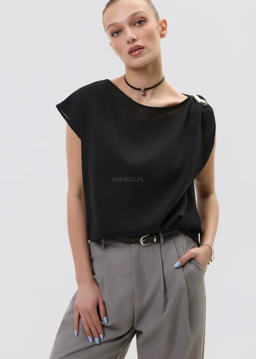 Czarna bluzka damska bez rękawów z luźnym krojem i ozdobnym zapięciem na ramieniu, elegancka minimalistyczna stylizacja.
