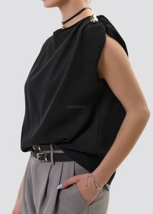 Czarna bluzka damska bez rękawów z luźnym krojem i ozdobnym zapięciem na ramieniu, elegancka minimalistyczna stylizacja.