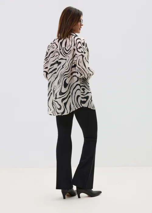 Koszula oversize w czarno-beżowy wzór abstrakcyjny, z długim rękawem i klasycznym kołnierzem, o luźnym kroju, stylizowana z dopasowanymi spodniami w nowoczesnym wydaniu.