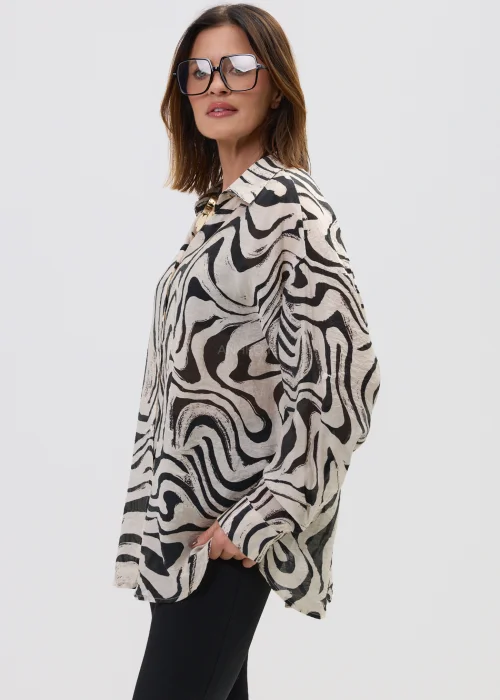 Koszula oversize w czarno-beżowy wzór abstrakcyjny, z długim rękawem i klasycznym kołnierzem, o luźnym kroju, stylizowana z dopasowanymi spodniami w nowoczesnym wydaniu.