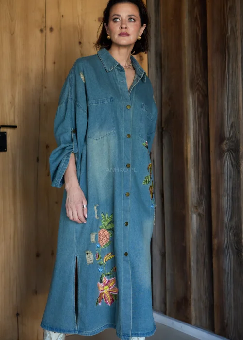 Sukienka koszulowa midi z denimu w odcieniu niebieskim, z haftowanymi kwiatami i przetarciami, o luźnym kroju oversize, stylizowana z kozakami w casualowym wydaniu.