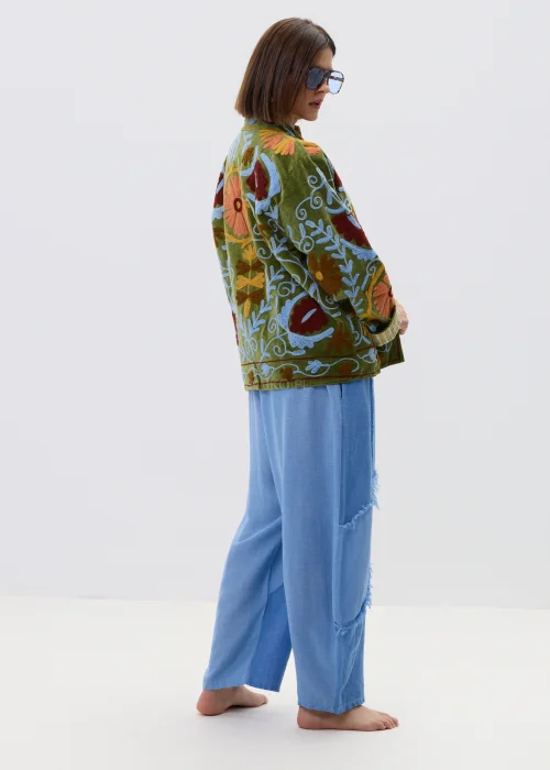 Zielona kurtka damska z bogatym haftem kwiatowym w odcieniach czerwieni, błękitu i beżu, zapinana na guziki, z wysokim kołnierzem i ozdobnymi mankietami.