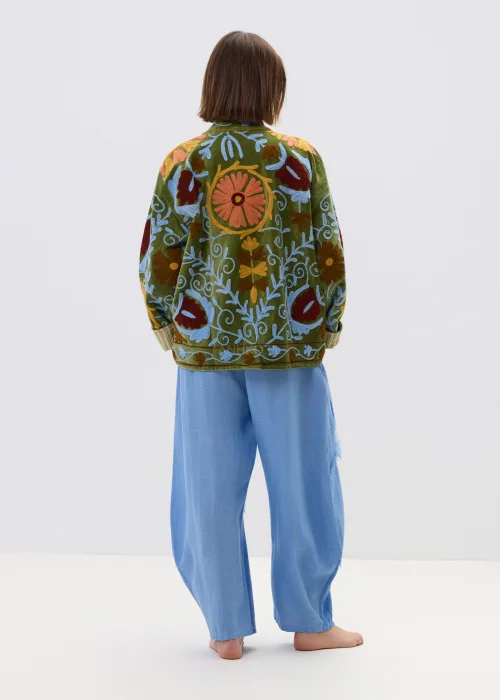 Zielona kurtka damska z bogatym haftem kwiatowym w odcieniach czerwieni, błękitu i beżu, zapinana na guziki, z wysokim kołnierzem i ozdobnymi mankietami.