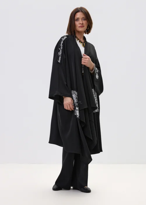 Czarne kimono damskie o luźnym, oversize’owym kroju z szerokimi rękawami i nadrukiem typograficznym, stylizacja w nowoczesnym, streetwearowym klimacie.