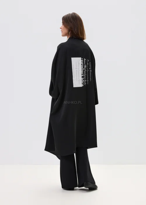 Czarne kimono damskie o luźnym, oversize’owym kroju z szerokimi rękawami i nadrukiem typograficznym, stylizacja w nowoczesnym, streetwearowym klimacie.