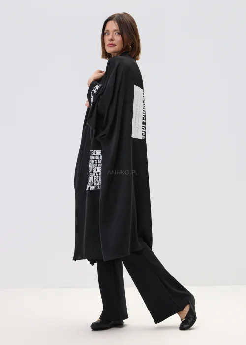Czarne kimono damskie o luźnym, oversize’owym kroju z szerokimi rękawami i nadrukiem typograficznym, stylizacja w nowoczesnym, streetwearowym klimacie.
