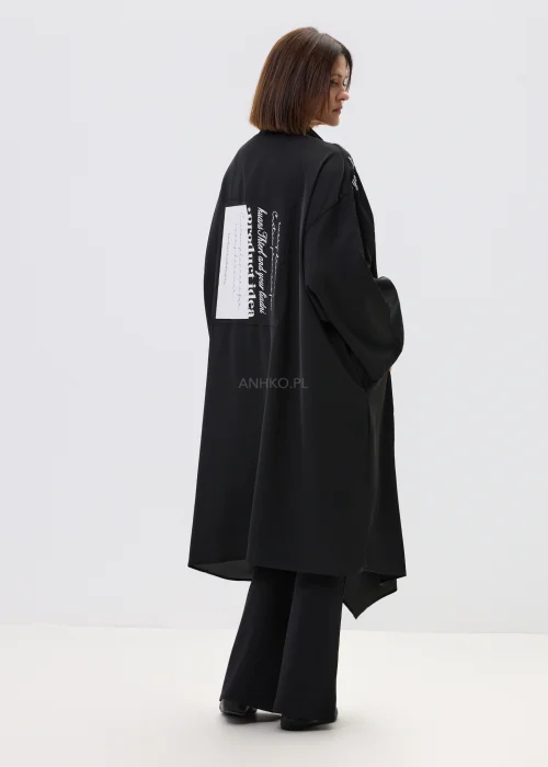 Czarne kimono damskie o luźnym, oversize’owym kroju z szerokimi rękawami i nadrukiem typograficznym, stylizacja w nowoczesnym, streetwearowym klimacie.