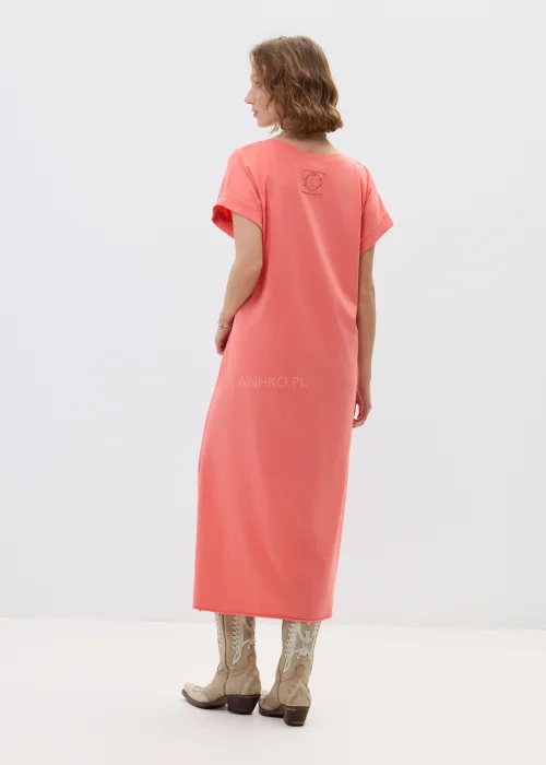 Koralowa sukienka maxi o luźnym, oversize’owym kroju z krótkim rękawem i dekoltem w serek, zestawiona z kowbojkami w stylizacji casual boho.
