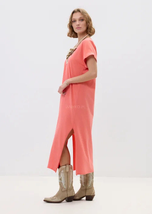 Koralowa sukienka maxi o luźnym, oversize’owym kroju z krótkim rękawem i dekoltem w serek, zestawiona z kowbojkami w stylizacji casual boho.
